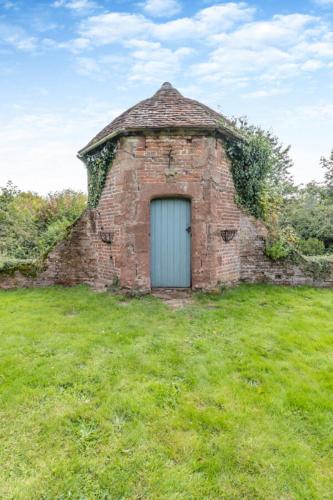 an old brick building with a blue door in a field at The Manor Shifnal Telford in Shifnal