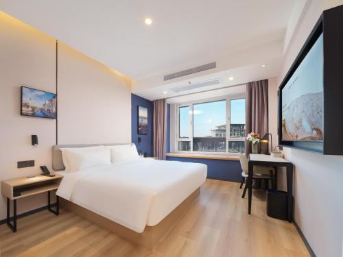 a bedroom with a large white bed and a desk at Atour X Hotel Dalian High-tech Zone Tengfei Software Park in Dalian