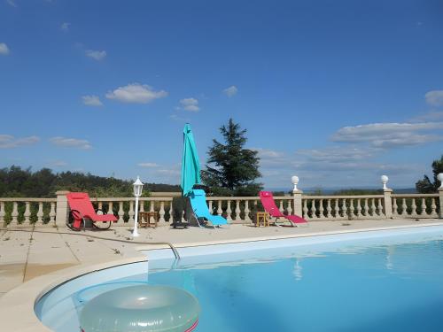 - une piscine avec des chaises et des parasols sur une terrasse couverte dans l'établissement Chez Louis, à Revel-Tourdan