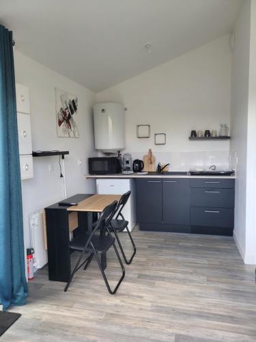 a kitchen with a wooden table and a desk at Le Studio in Saint-Pierre-Montlimart