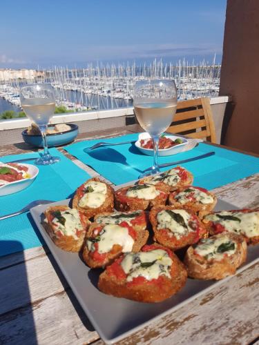 une table avec une assiette de nourriture et des verres de vin dans l'établissement gruissan la belle rive droite, à Gruissan