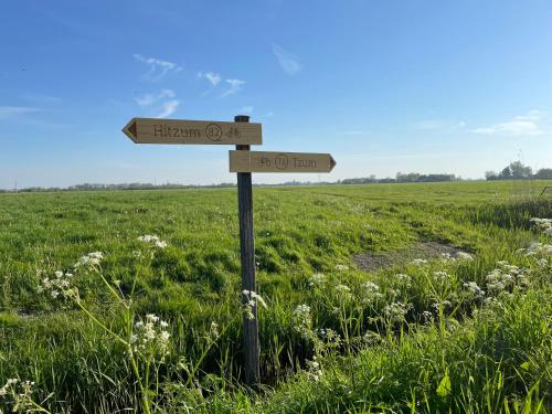 a wooden sign in the middle of a field at Bed and Breakfast de Salix in Hitzum