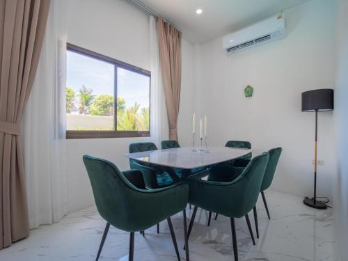 ラワイビーチにあるLeivi Villa 3 bedroomsのダイニングルーム(ガラステーブル、緑の椅子付)