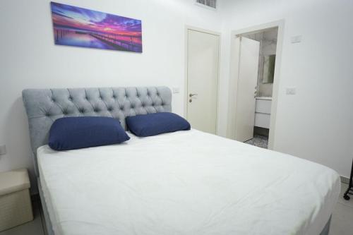 a bedroom with a large white bed with blue pillows at גרדניה פריים in Eilat
