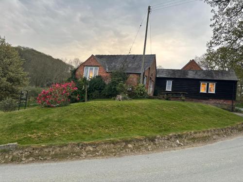 a house on a hill with a green yard at Pandy Barn Berriew in Welshpool
