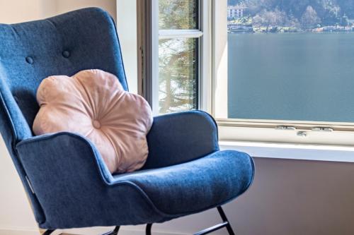 a blue chair with a pillow in a room with a window at Magnificent apartment on Lake Lugano, Morcote in Morcote