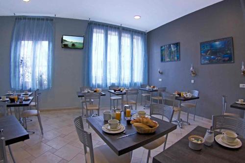 a dining room with tables and chairs and windows at Le Strasbourg Hotel in Montpellier