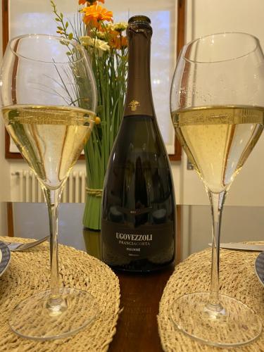 two glasses of white wine next to a bottle of wine at La Chiocciola Viaggiatrice in Palazzolo sullʼOglio