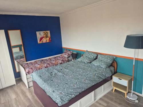 une chambre avec un lit et un mur bleu dans l'établissement T3, 65 m2, proche de la gare et des commerces, à Toulouse