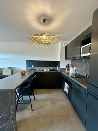 une cuisine avec un grand comptoir et un lustre dans l'établissement Appartement neuf confortable, à LʼÎle-Rousse