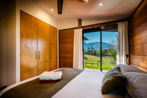 a bedroom with a bed and a large window at Promised Land Retreat in Bellingen