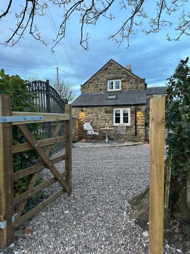 a gate to a stone cottage with a house at Cedar Cottage newly renovated cottage in Matlock