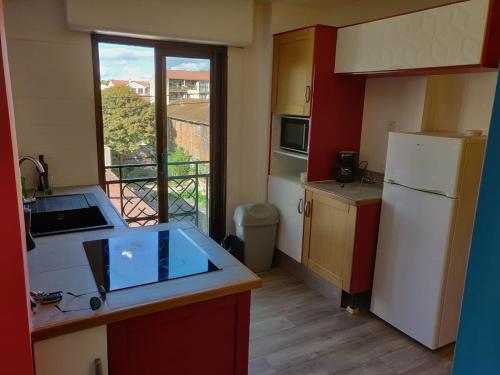 une cuisine avec un réfrigérateur blanc et une fenêtre dans l'établissement T3, 65 m2, proche de la gare et des commerces, à Toulouse