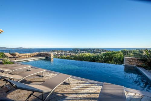 - une piscine avec des chaises longues et l'océan dans l'établissement Villa Soleil d'Or, golfe de St Tropez, vue mer panoramique, à Cavalaire-sur-Mer