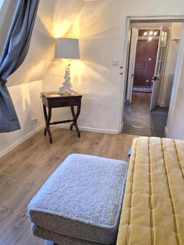a bedroom with a bed and a table with a lamp at les Myrrhophores et Spa, Chambres d'Hôtes et Gîtes de charme in Abbeville