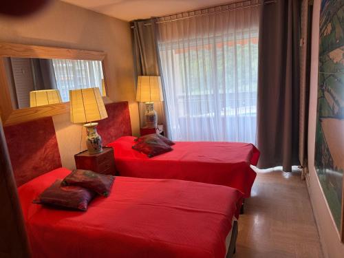 deux lits dans une chambre d'hôtel avec des draps rouges dans l'établissement 2 pièces Mandelieu, à Mandelieu-la-Napoule