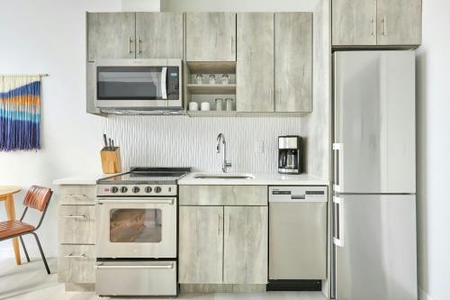 a kitchen with stainless steel appliances and a white refrigerator at Sonder by Marriott Bonvoy Zuni Apartments LoHi in Denver