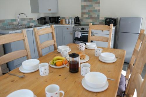 a kitchen with a wooden table with plates and cups at Prince Rupert's cottage with garden in Sibbertoft