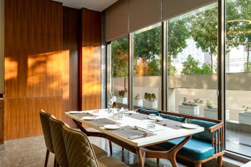 a dining room with a table and chairs and windows at The Paradise Bliss - A Luxury Hotel & Spa in Udaipur in Udaipur