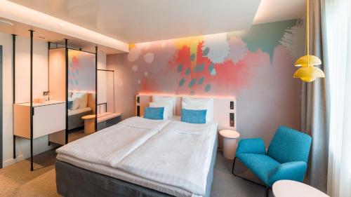a bedroom with a large bed and a blue chair at Break Sokos Hotel Flamingo in Vantaa