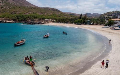 people standing on a beach with boats in the water at Casa Ida 2 Tarrafal, Cape verde in Tarrafal