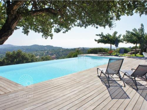 2 chaises assises sur une terrasse en bois à côté d'une piscine dans l'établissement Villa Petra Vuer Mer & Piscine, à Zonza