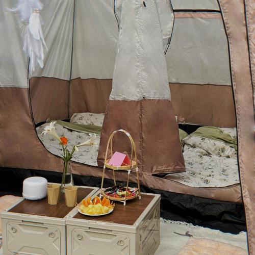 a table with a bowl of fruit and a bed at Nú Camping in Minh Nông
