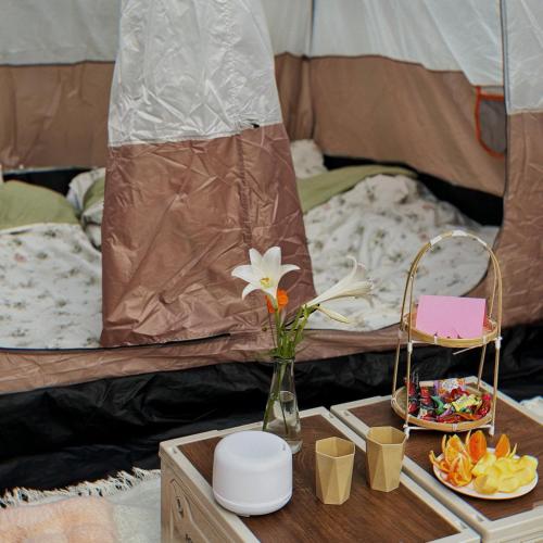 a table with a vase of flowers and a tray of food at Nú Camping in Minh Nông