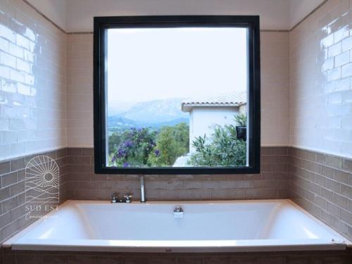 une baignoire dans une salle de bain avec une grande fenêtre dans l'établissement Villa Petra Vuer Mer & Piscine, à Zonza