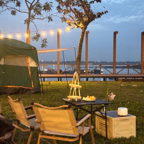 a tent and two chairs and a table with at Nú Camping in Minh Nông