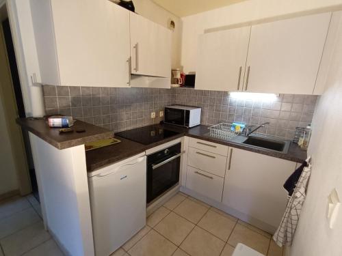 une petite cuisine avec des armoires blanches et un micro-ondes dans l'établissement Charming 3-star furnished tourist accommodation in Barr, à Barr