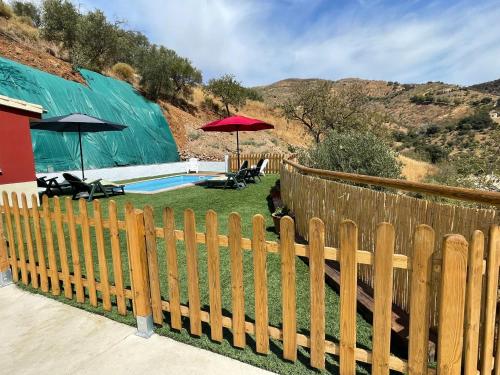 a wooden fence in front of a yard with a pool at Casa Rural El Burro Bajo in Casabermeja