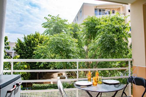 - un balcon avec une table, des chaises et des arbres dans l'établissement walk to beach with AC and swimpool, à Cagnes-sur-Mer