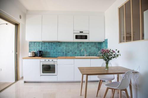 une cuisine avec des armoires blanches et une table en bois dans l'établissement Marina Baie des Anges Ducal SEA VIEW AC, à Villeneuve-Loubet