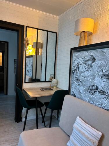 Cette chambre comprend une table, un miroir et un canapé. dans l'établissement Le Chanzy Proche des Thermes et de la Gare, à Rochefort