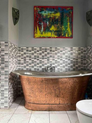 a bath tub in a bathroom with a painting on the wall at Quirky house in Manchester