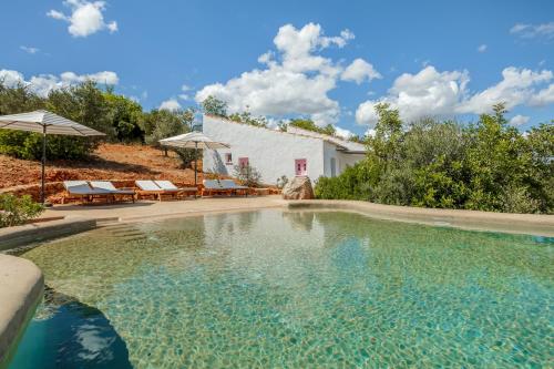 a swimming pool with chairs and umbrellas next to a house at Casa da Encosta in Silves