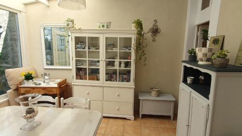 a kitchen with a white cabinet and a table and a dining room at La maison d`hôtes de Constance in Le Mans
