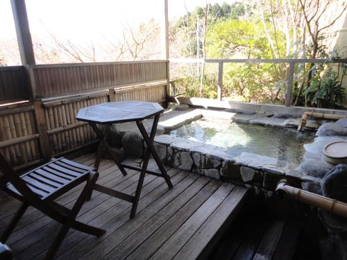 a table and a chair on a deck with a pond at Yoshimatsu in Hakone