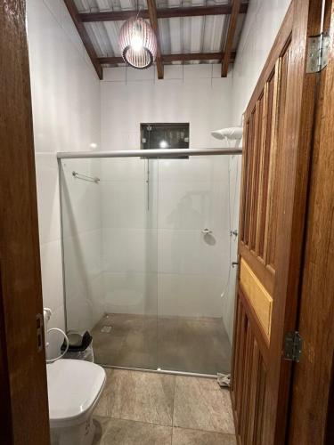 a glass shower in a bathroom with a toilet at Chalé aconchegante no Prado - Ar, Wi-Fi e ótima localização in Prado