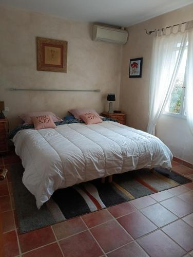 - une chambre dotée d'un grand lit avec des draps blancs et des oreillers roses dans l'établissement Belle Villa piscine 4 personnes, à Vestric-et-Candiac