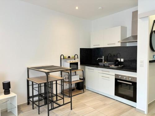 une cuisine avec des armoires blanches et une table à l'intérieur dans l'établissement Cozy studio - Downtown Vallauris, à Vallauris