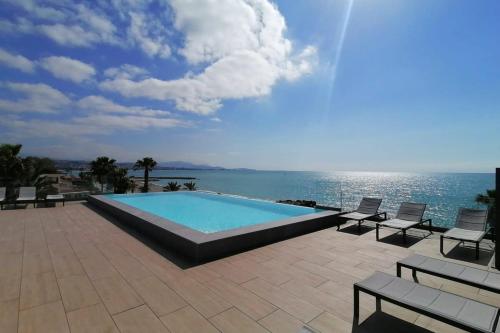 une piscine avec des chaises et une vue sur l'océan dans l'établissement Studio feet in the water friendly cozy and unique, à Villeneuve-Loubet
