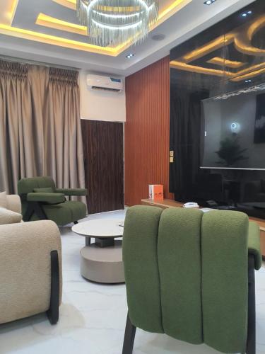 a room with chairs and a tv and a table at Grazioli 3Bedroom Apartment 'Sicily' in Enugu