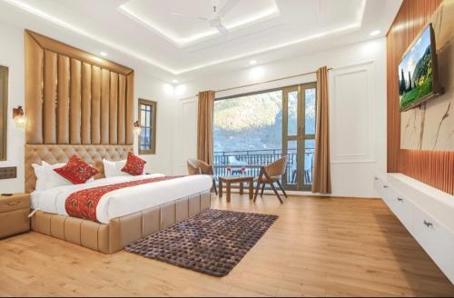a bedroom with a bed and a table and a television at Hotel Falcon heights in Anantnāg
