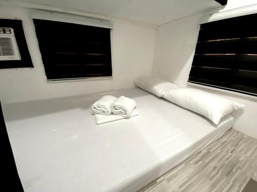 a white room with two towels on a boat at Nature Home Suites in Lunao