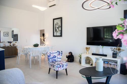 - un salon avec une table, des chaises et une télévision dans l'établissement Sumptuous villa with sea view and its renovated outbuilding in the heart of, à Théoule-sur-Mer