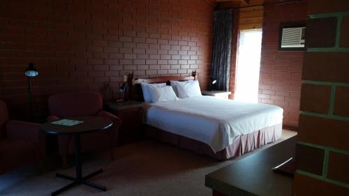 ein Schlafzimmer mit einem Bett, einem Stuhl und einem Fenster in der Unterkunft Highway One Motel in Port Augusta