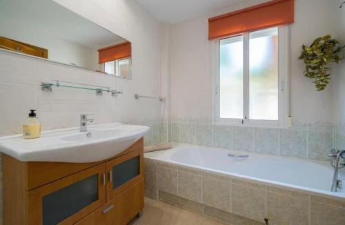 a bathroom with a sink and a tub and a window at Casa Violetta in Alicante