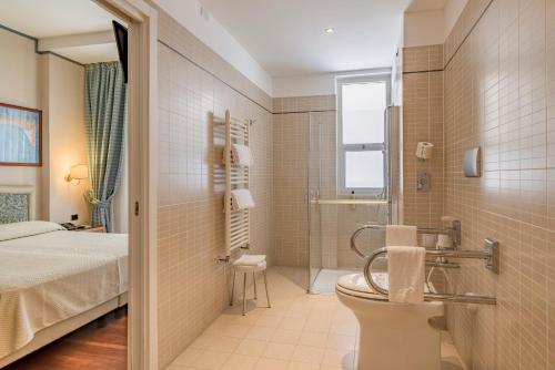 a bathroom with a bed and a toilet and a shower at Hotel Garden Lido in Loano
